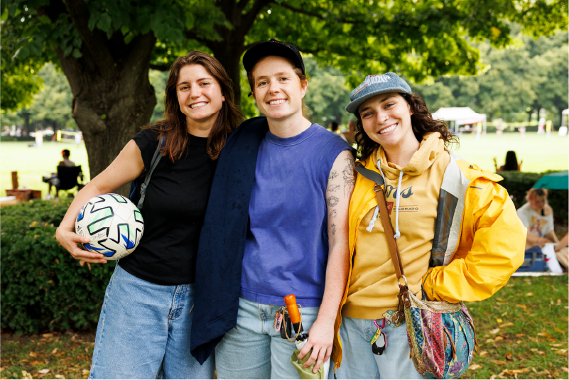 Three museum visitors standing in the sculpture park with a soccer ball