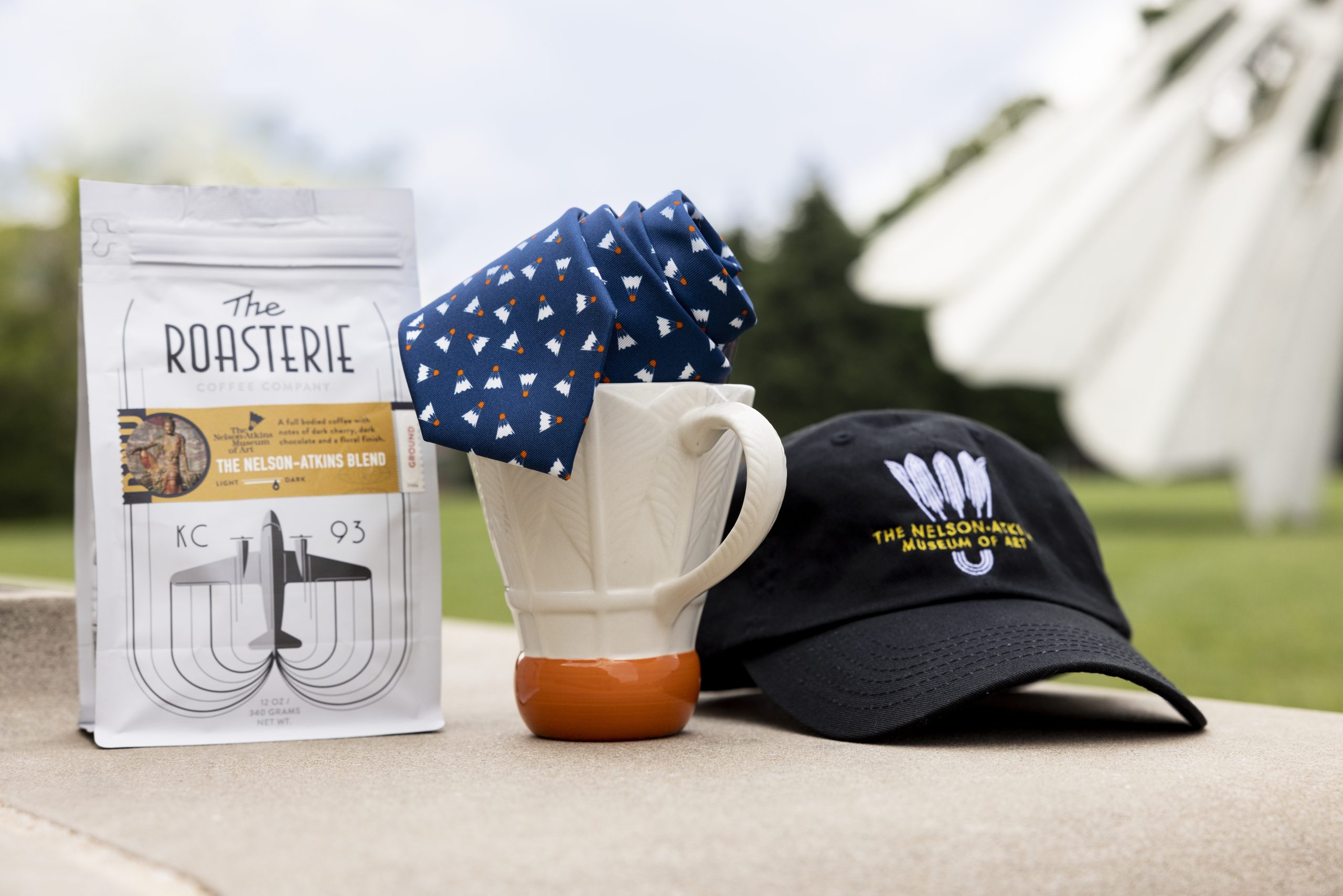Photo of items found in museum store, a coffee bag, coffee mug, and shuttlecock hat