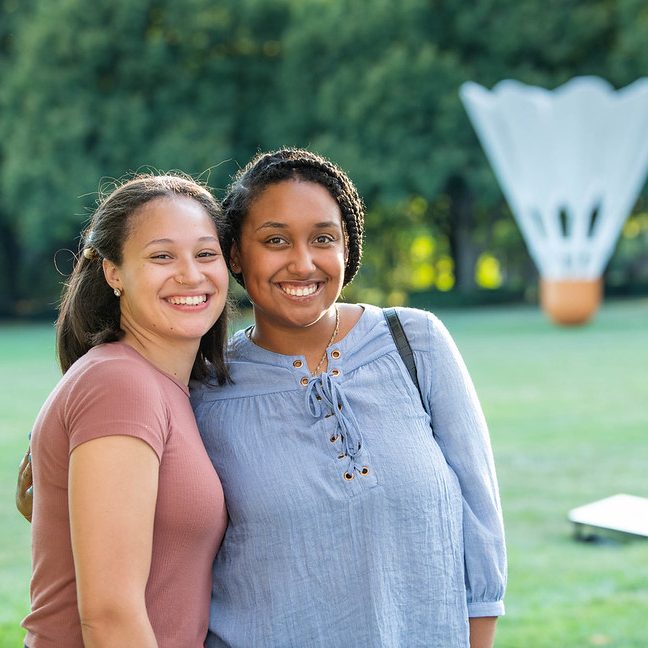 Two women pose for a photo in front of the Shuttlecock sculpture at the Nelson-Atkins.