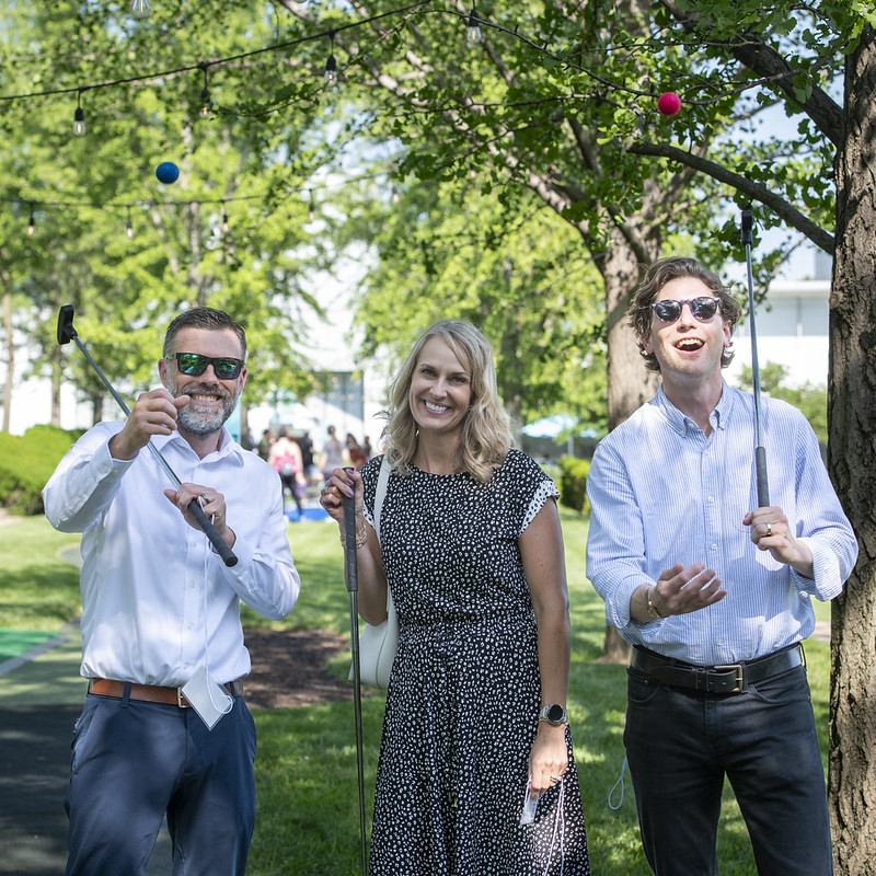 Two men and a woman pose playfully with golf clubs on the Nelson-Atkins Art Course.
