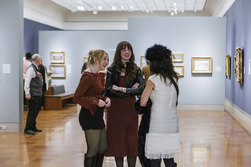 Three woman standing in art gallery.