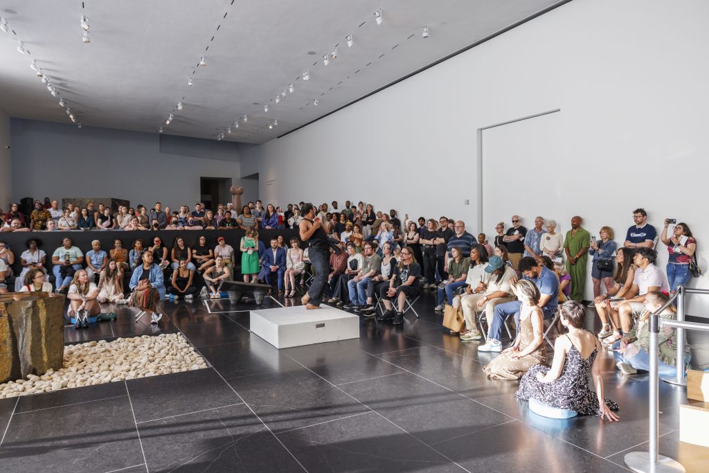 A crowd gathers to watch dancers perform in Noguchi Court at The Nelson-Atkins Museum of Art.