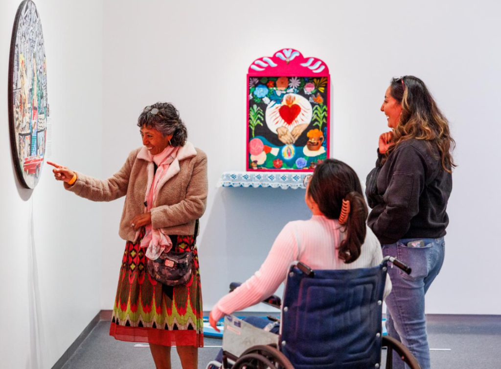 Three women smile at a work of art in an exhibition at The Nelson-Atkins Museum of Art.
