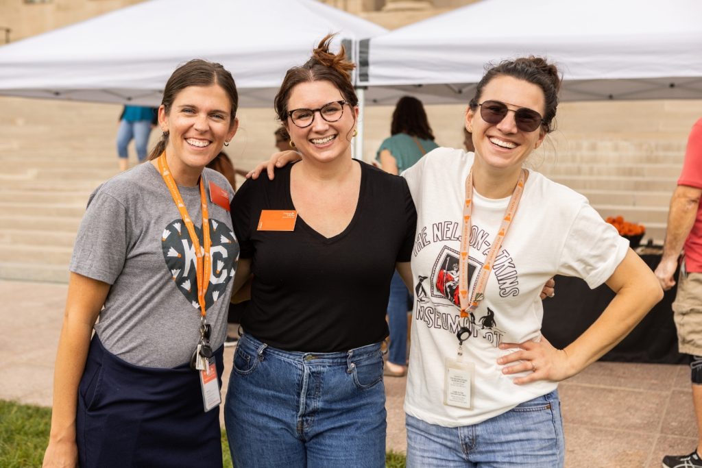 Three museum staff smiling in the sculpture park