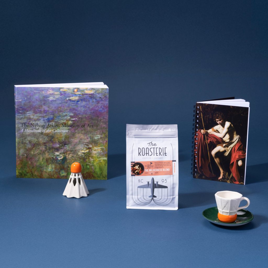 Items including coffee, coffee mug, notebook, and ornament from museum store on blue background.
