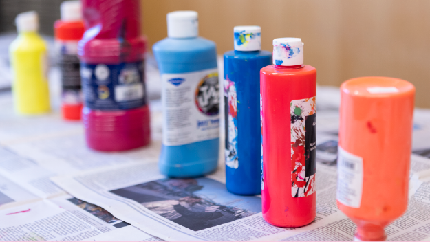 A person adjusting paintbrushes in their apron.
