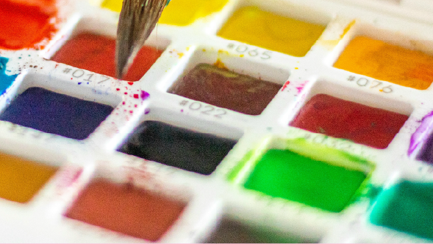 Colored pencils layed out over a drawing on paper.