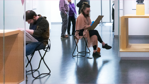 Multiple colors of pain on a table with pant brushes in them.