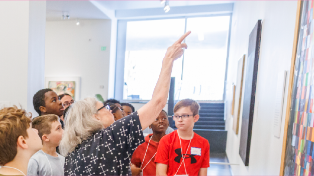 Multiple colors of pain on a table with pant brushes in them.