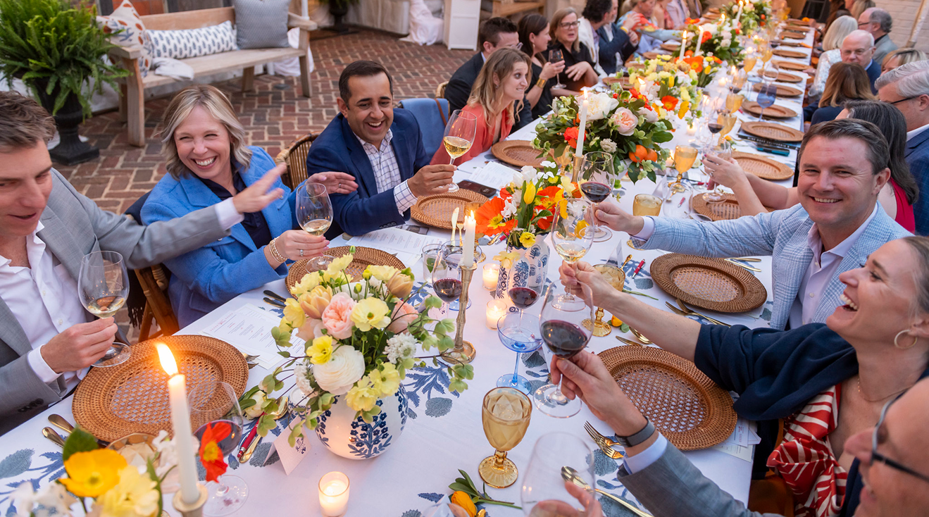 A group of museum supporters toasting at a wine dinner.