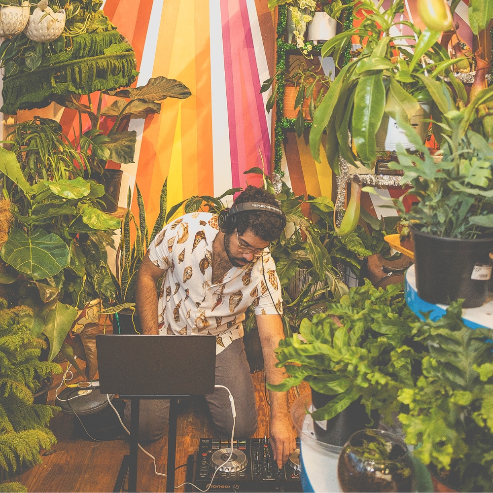 DJ Jon Sabillon performs amidst plants and foilage 