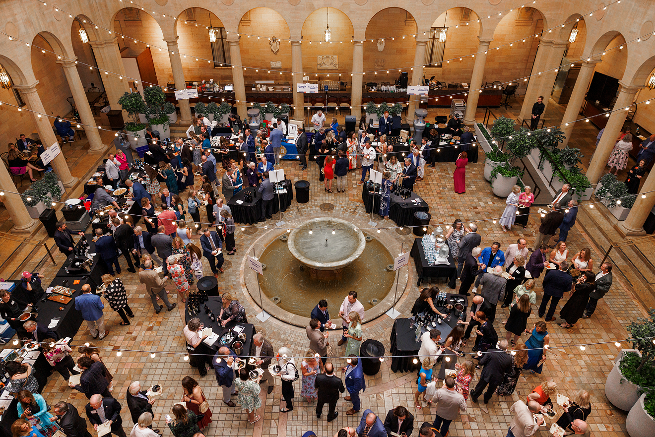 A large group of people enjoying cocktails and food in an italian styled court
