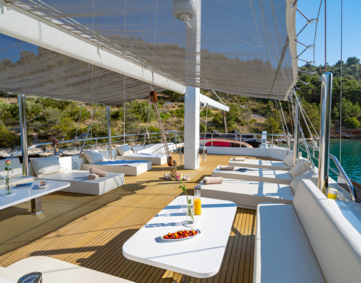 A picture on a yacht with chairs and food set up.
