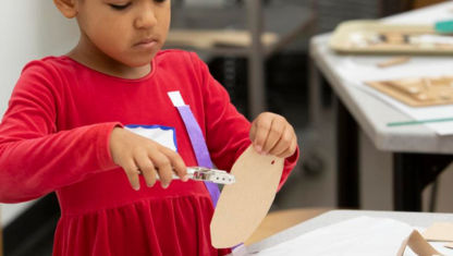 Multiple colors of pain on a table with pant brushes in them.
