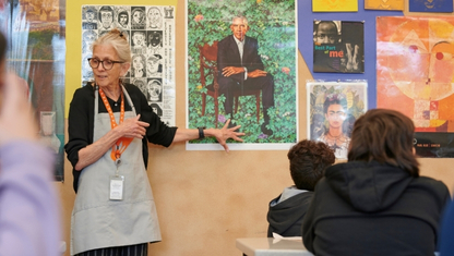 A person adjusting paintbrushes in their apron.