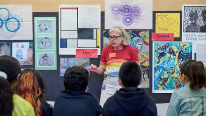 A person adjusting paintbrushes in their apron.