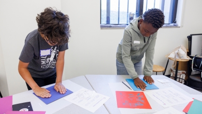 Multiple colors of pain on a table with pant brushes in them.