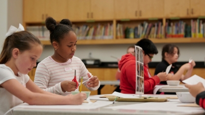 A person adjusting paintbrushes in their apron.