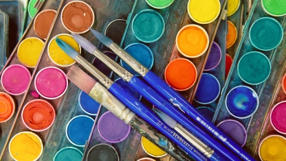 Colored pencils layed out over a drawing on paper.