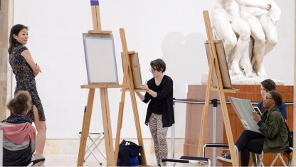 A person adjusting paintbrushes in their apron.