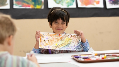 A person adjusting paintbrushes in their apron.