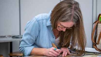A person adjusting paintbrushes in their apron.